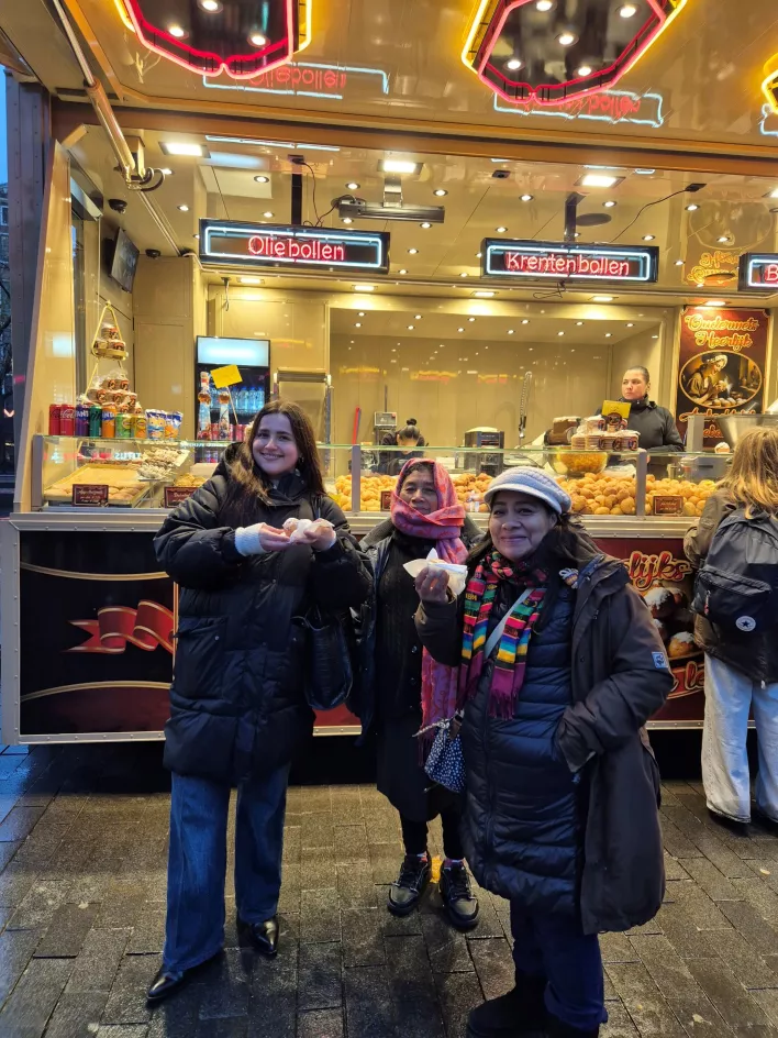 Norma, Carmelita en vrijwilliger Sara eten een oliebol